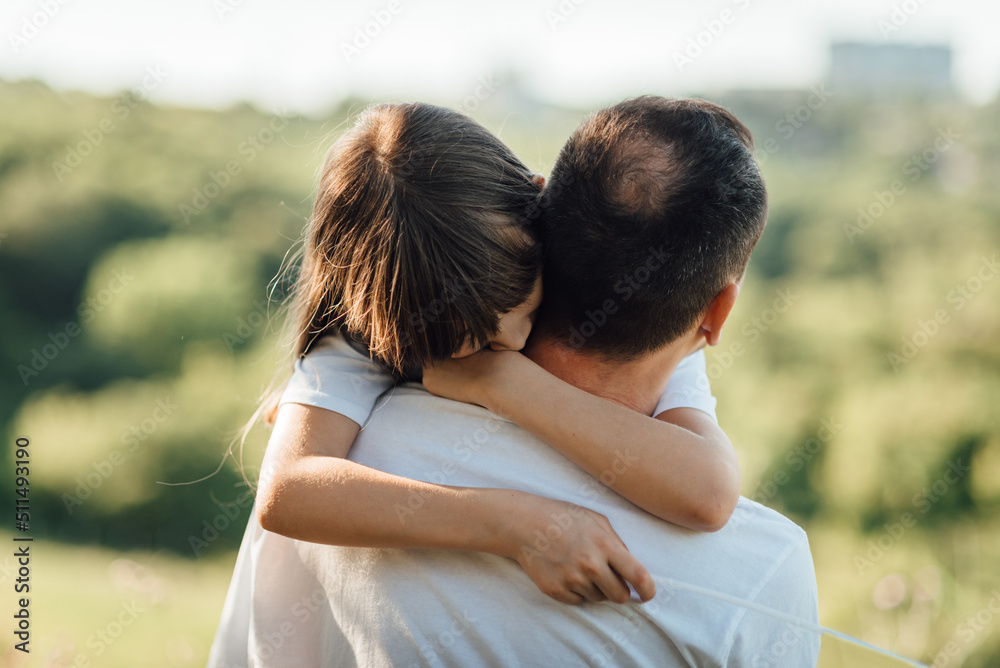 Young girl hugs her father putting arms around his neck Young girl hugs her father putting arms around his neck