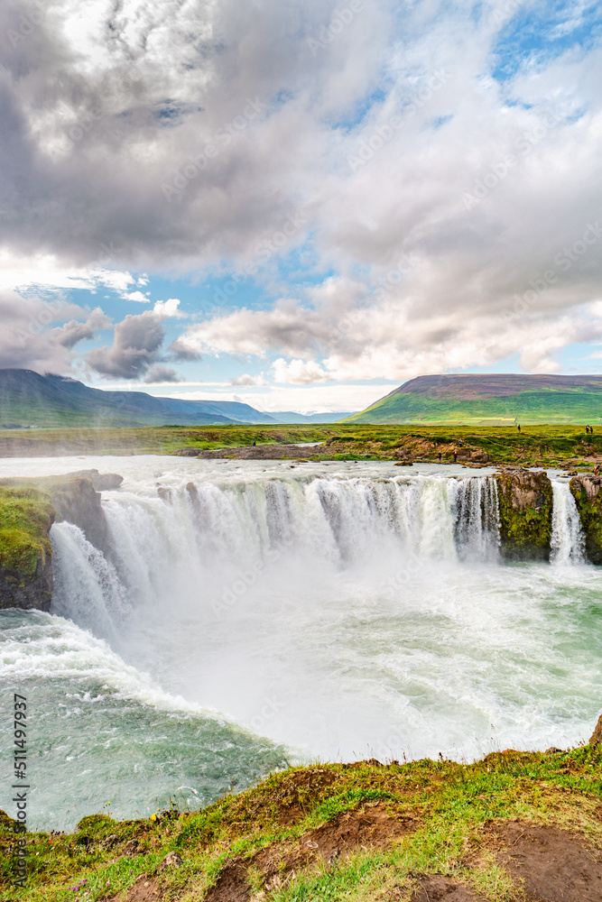 Cover page with popular tourist attraction waterfall Godafoss in Iceland with tourists watching the sightseeing, summer, dramatic sky. Cover page with popular tourist attraction waterfall Godafoss in Iceland with tourists watching the sightseeing, summer, dramatic sky.