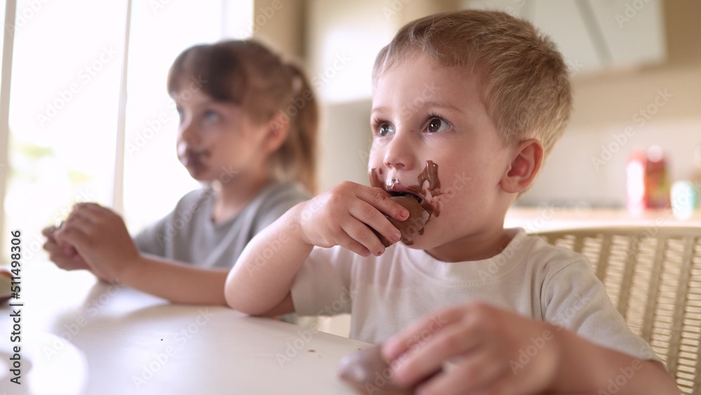 children eat chocolate. dirty little baby kids in the kitchen eating chocolate in the morning. happy family eating sweets kid dream concept. baby dirty face lifestyle eating chocolate cocoa children eat chocolate. dirty little baby kids in the kitchen eating chocolate in the morning. happy family eating sweets kid dream concept. baby dirty face lifestyle eating chocolate cocoa