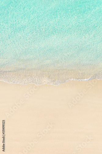 Aerial view of yellow umbrella on sandy beach. Summer and travel concept. Blue, turquoise transparent water surface of ocean, sea, lagoon. Aerial, drone view. vertical