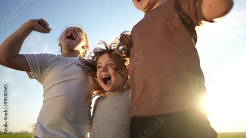 group of kids team hugging a jumping and rejoicing outdoors. happy family teamwork kid dream concept. family lifestyle children sisters brothers have fun hugging in the park in nature