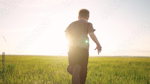 boy running in the park. happy family a kid dream concept. child son boy 8 years old running on the grass in the summer in the park rear view at sunset. kid run in nature lifestyle