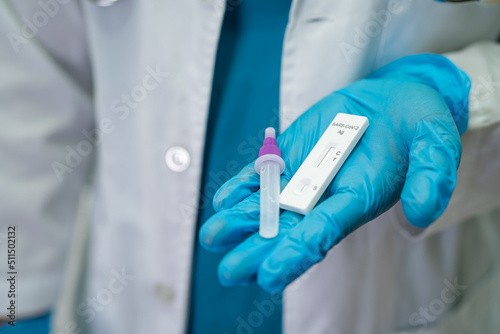 Asian doctor in PPE suit holding Saliva Antigen Test Kit for check Covid-19 coronavirus in hospital.