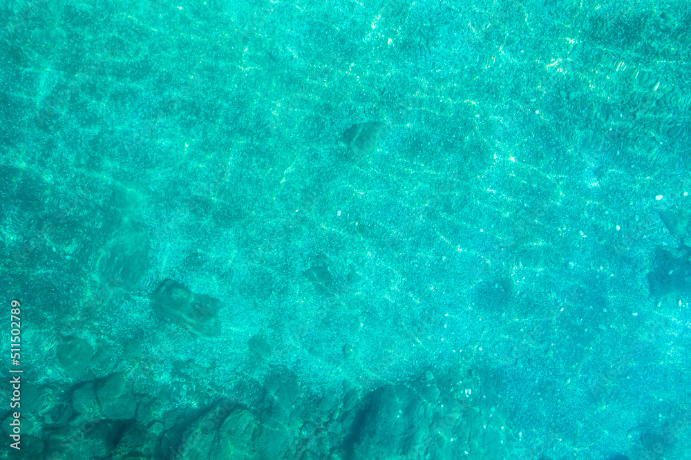 Blue, turquoise transparent water surface of ocean, sea, lagoon. Horizontal background. Top view of sand beach. Aerial, drone view