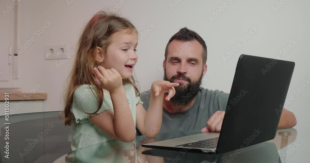 Father helps little daughter do homework on laptop at home Father helps little daughter do homework on laptop at home