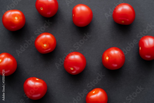 Top view of natural whole cherry tomatoes on black background.