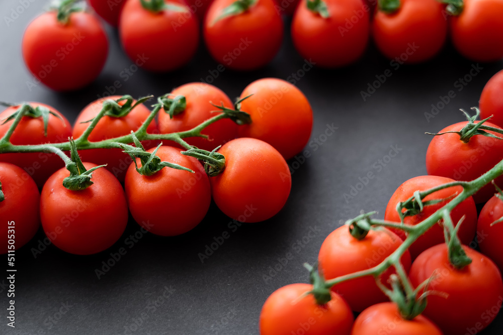 Close up view of fresh cherry tomatoes on branches on black background. Close up view of fresh cherry tomatoes on branches on black background.