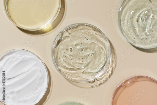 Various cosmetic products in Petri dishes on beige background view from above photo