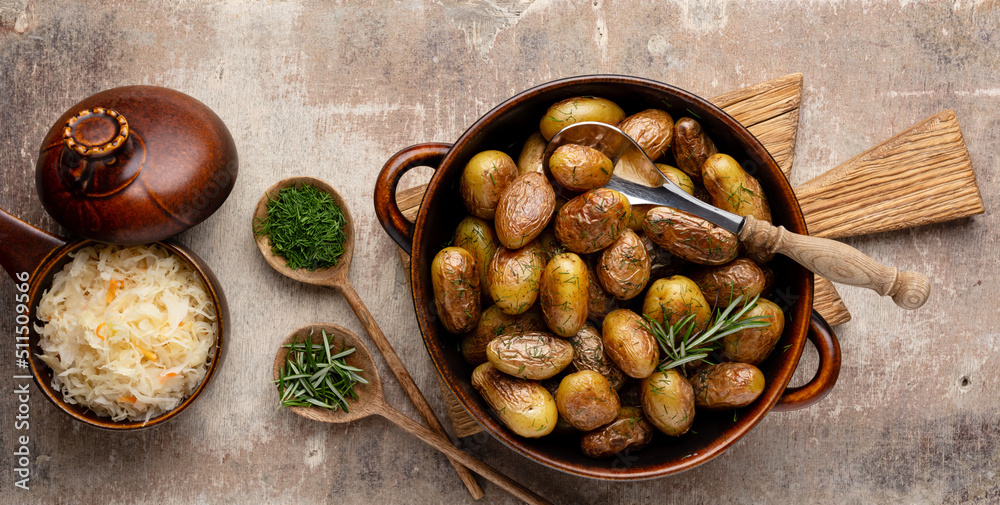 Fototapeta premium Pan filled with roasted potatoes shot on rustic wooden table.