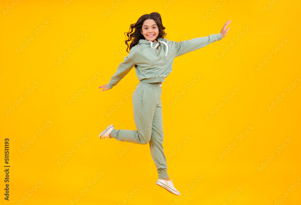 Full length of attractive cheerful girl in sport wear isolated over yellow background. Sportwear for teenager child.