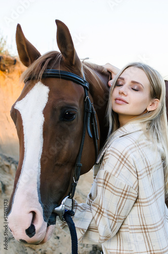 Young woman hugs her horse close-up on ranch. Pleasure, love and care for animals, nature country lifestyle. warm natural brown tones in sunset