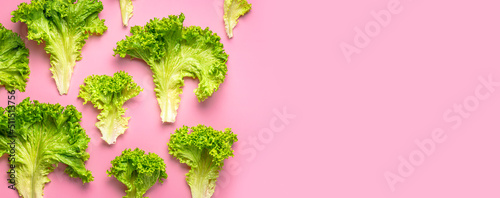Foto Pattern from Fresh green lettuce leaves on bright pink background flat lay top view