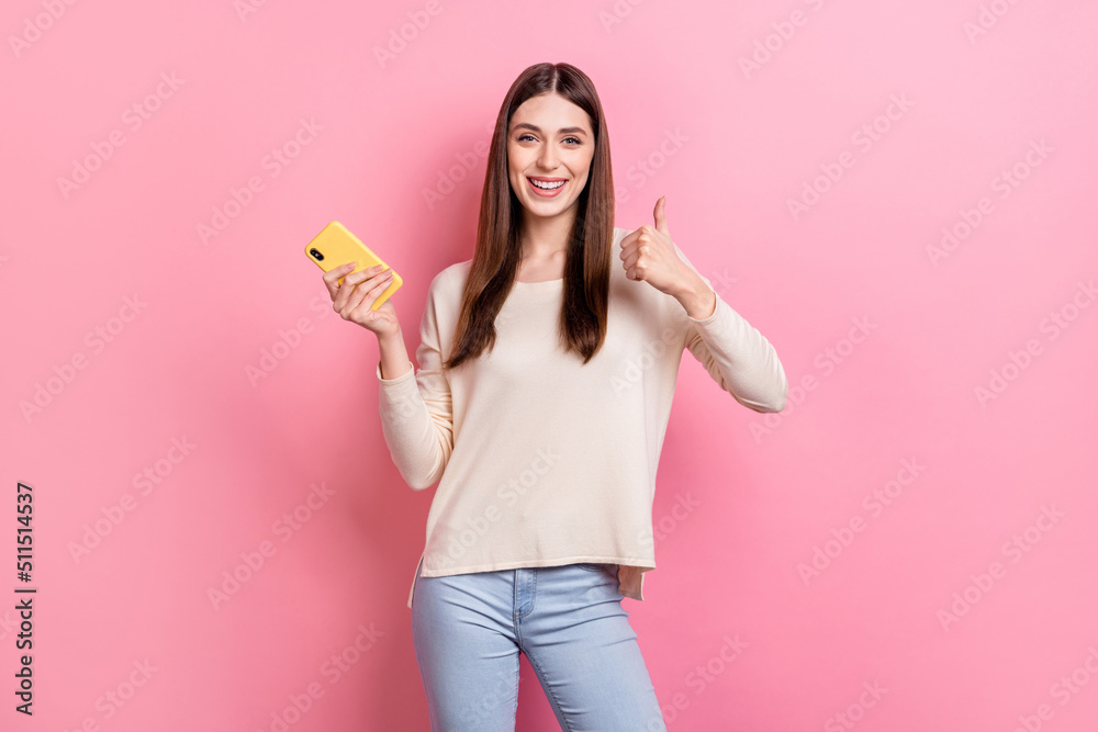 Portrait of attractive cheerful brown-haired girl using app showing thumbup isolated over pink pastel color background Portrait of attractive cheerful brown-haired girl using app showing thumbup isolated over pink pastel color background