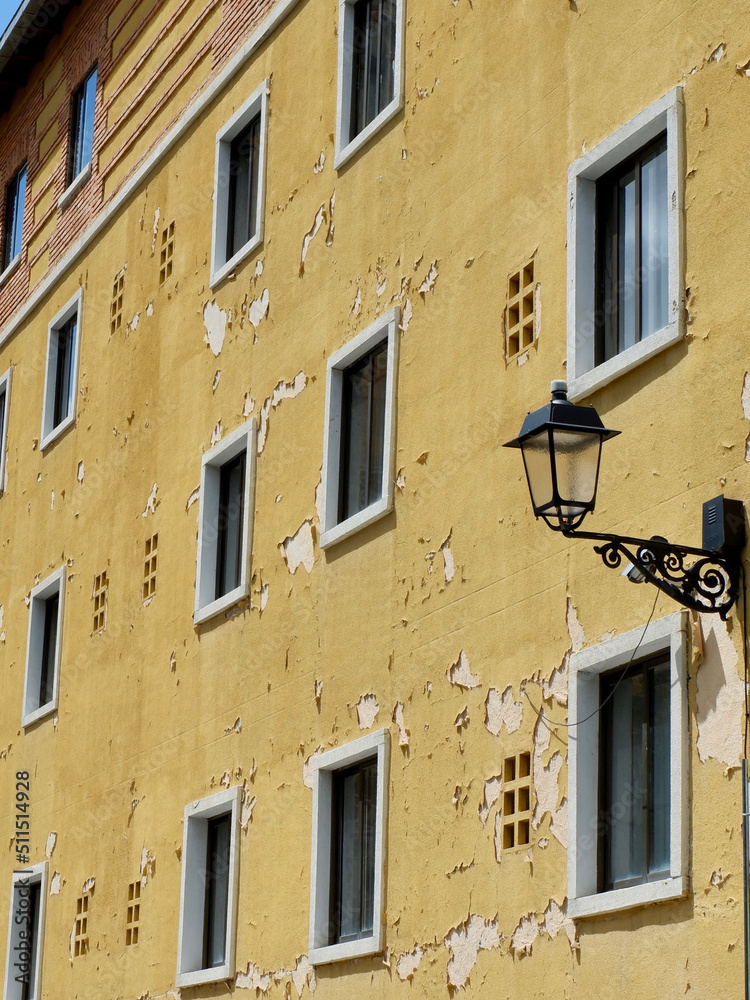 Weathered facade with peeling yellow paint in the old center of Segovia, Spain