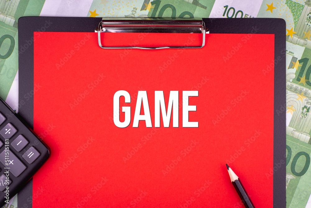 GAME - word on the background of money, a notepad and a pencil with a calculator. Business concept (copy space). GAME - word on the background of money, a notepad and a pencil with a calculator. Business concept (copy space).