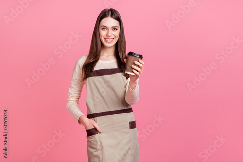 Portrait of attractive cheerful girl manager serving cappuccino latte isolated over pink pastel color background