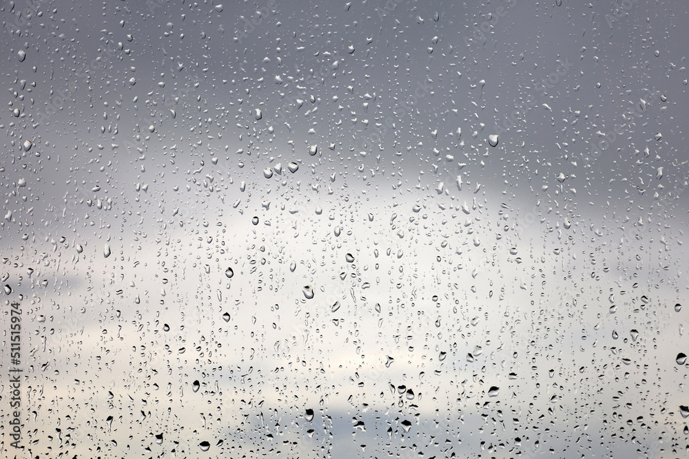 Raindrops on the window glass on blurred background of storm sky with clouds. Water drops, weather during rain Raindrops on the window glass on blurred background of storm sky with clouds. Water drops, weather during rain