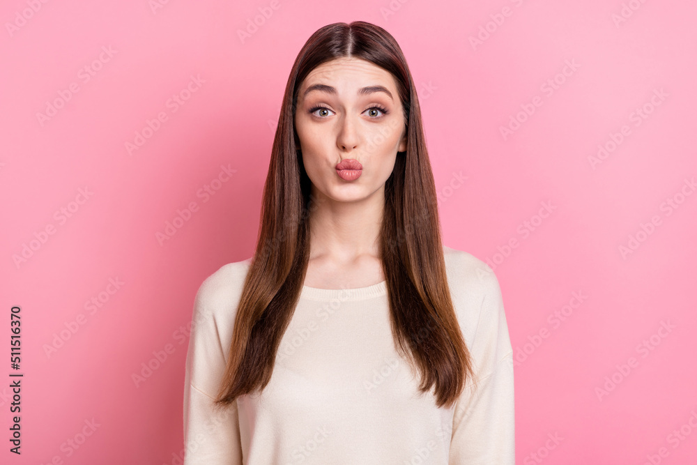 Fototapeta premium Portrait of attractive flirty brown haired girl sending air kiss isolated over pink pastel color background