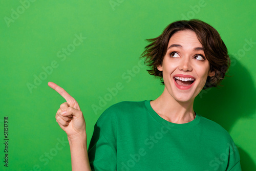 Photo of sweet dreamy young lady dressed casual t-shirt looking pointing empty space isolated green color background