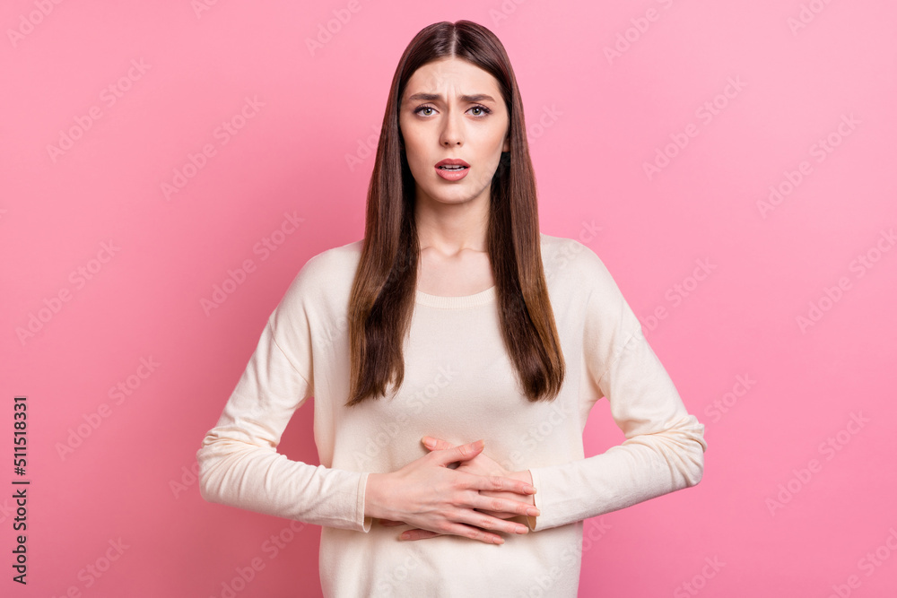 Obraz premium Portrait of attractive sick girl touching belly feeling bad isolated over pink pastel color background