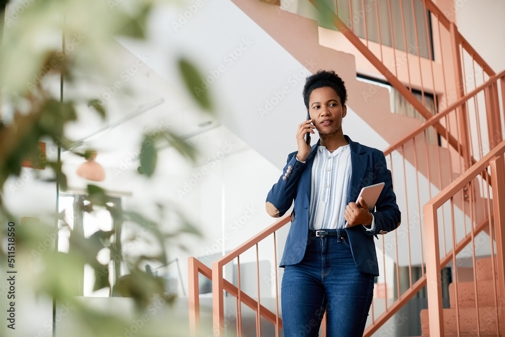 Black female entrepreneur talks on the phone in hallway. Black female entrepreneur talks on the phone in hallway.
