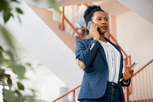 Black businesswoman making phone call in lobby of an office building.