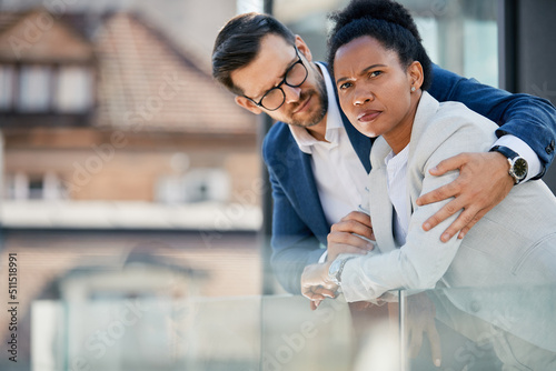 Distraught black businesswoman and her colleague on balcony of an office building.