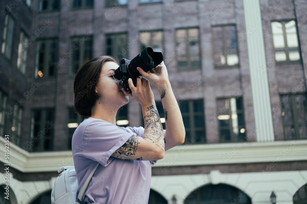 Young Girl Photographer Takes Pictures of City Architecture. Tattooed Girl with Camera Takes Pictures in City Center