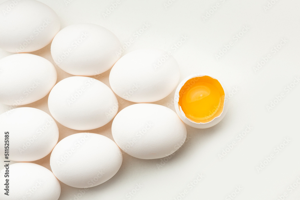 White eggs on a white background, one egg is broken, unlike the others. White eggs on a white background, one egg is broken, unlike the others.