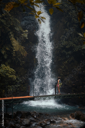 Woman on a bridge admiring a waterfall in front