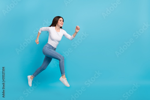Photo of charming pretty lady dressed white shirt jumping high running empty space isolated blue color background
