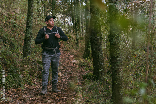 man walking through a forest wearing a backpack