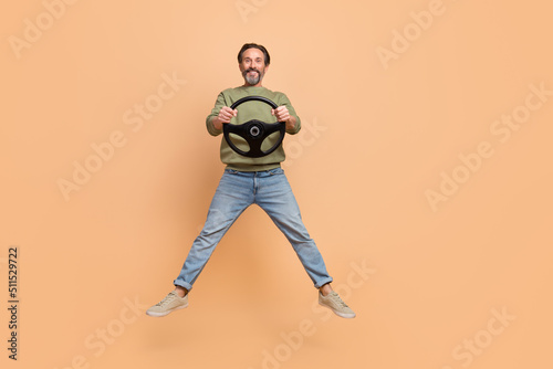 Full size portrait of satisfied excited man hold wheel have good mood isolated on beige color background