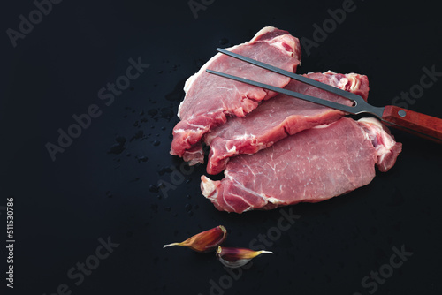 Fresh Raw Meat and meat fork on dark background.