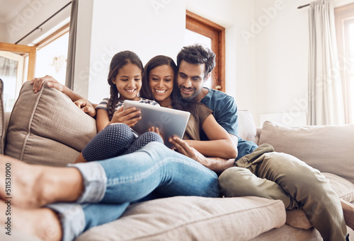 Making screen time bonding time. Shot of a mother and father using a digital tablet with their daughter on the sofa at home.