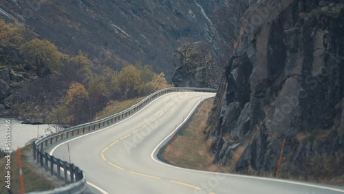 Narrow two-lane country road winds between the steep rocky slopes. Slow-motion, pan forward. photo