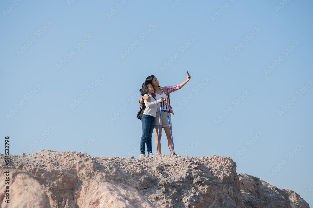 family travel- hikers with backpack looking at mountains, mother with child, Taking selfie,happy mother and girl making self portrait in the mountains, woman holding smartphone camera to take picture. family travel- hikers with backpack looking at mountains, mother with child, Taking selfie,happy mother and girl making self portrait in the mountains, woman holding smartphone camera to take picture.