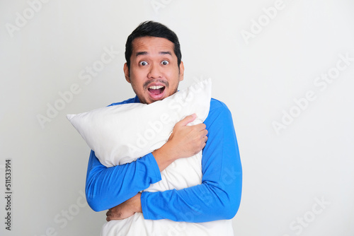 Adult Asian man hugging a pillow while showing happy face expression