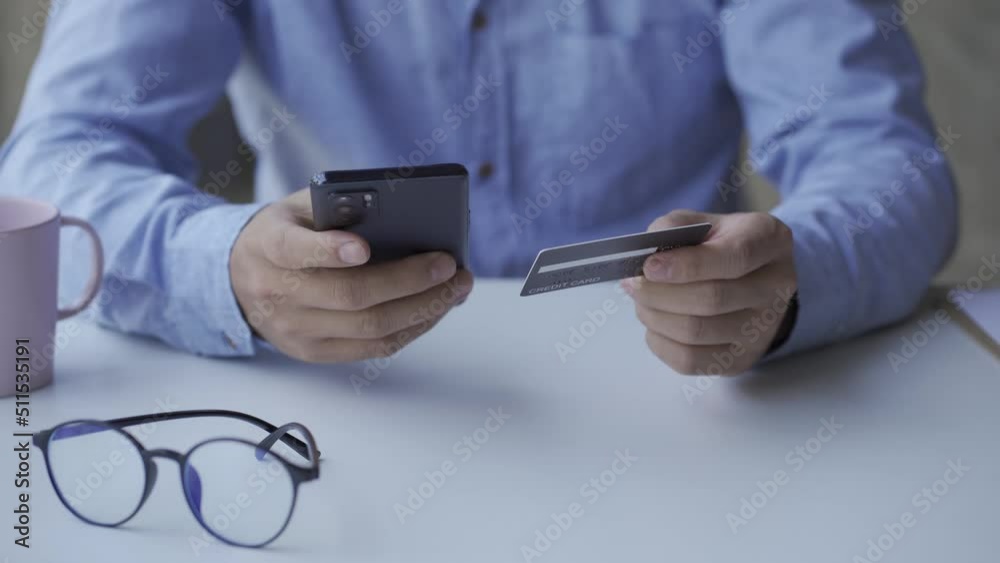 business people shopping online with credit card man paying with credit card on smartphone In hand, doing shopping at home, office. business people shopping online with credit card man paying with credit card on smartphone In hand, doing shopping at home, office.