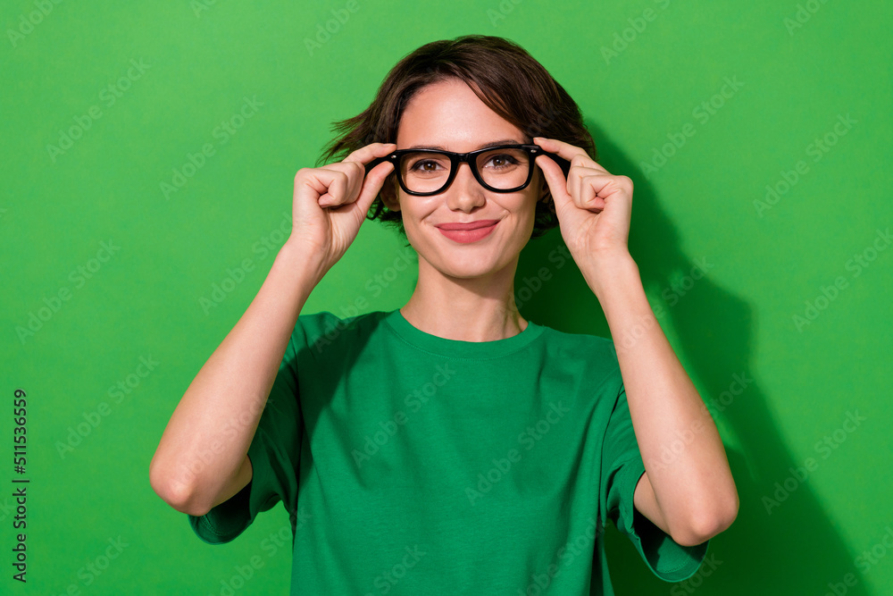 Photo of sweet charming woman wear casual t-shirt arms spectacles smiling isolated green color background Photo of sweet charming woman wear casual t-shirt arms spectacles smiling isolated green color background
