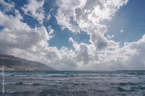 Bright blue ocean in a cloudy blue sky, with city Vlore on the horizon in albania