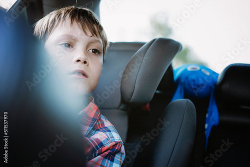 Sad bored caucasian boy travelling by car sitting by open window