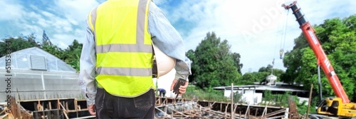 An engineer or worker wearing a life jacket holds a walkie-talkie and a white cap in hand. for safety working on the construction site background