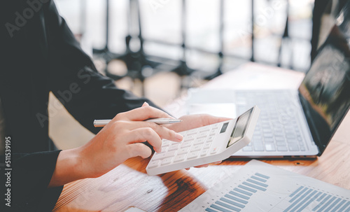 business woman or accountant who are using a calculator to calculate business data Accounting documents and laptop computer at the office business idea