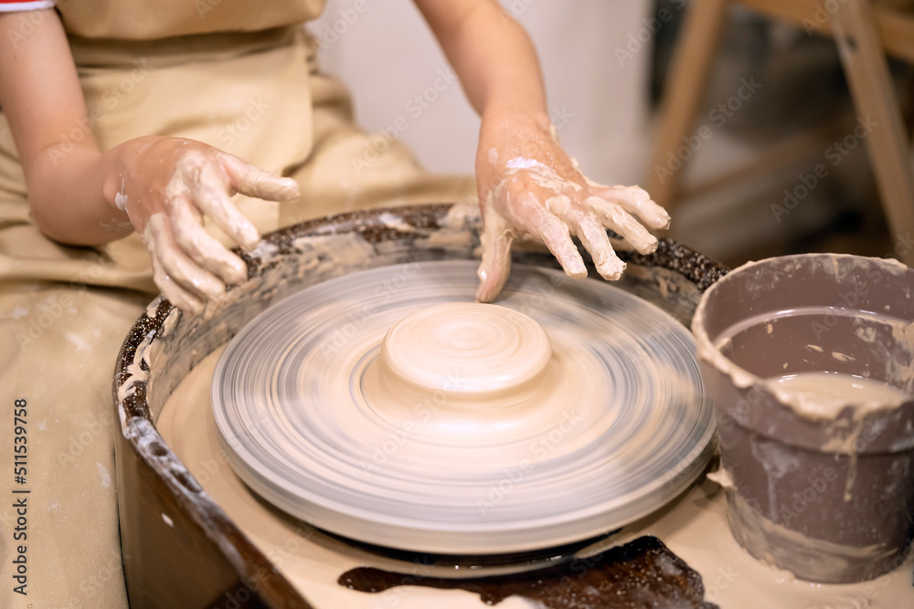 Human hands and potter's wheel. Hands of a child making a cup on a potter's wheel. Human hands and potter's wheel. Hands of a child making a cup on a potter's wheel.