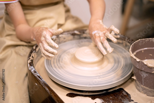 Human hands and potter's wheel. Hands of a child making a cup on a potter's wheel.