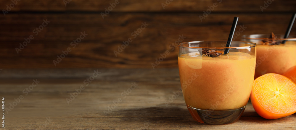 Tasty persimmon smoothie with anise and straw on wooden table, space for text. Banner design Tasty persimmon smoothie with anise and straw on wooden table, space for text. Banner design