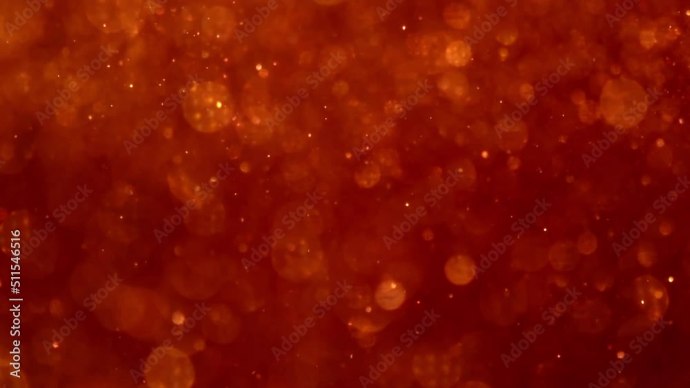 Golden Particles Movement In Red liquid. Gold dust particles and bokeh moving slowly in red fluid. Abstract relaxing background. 