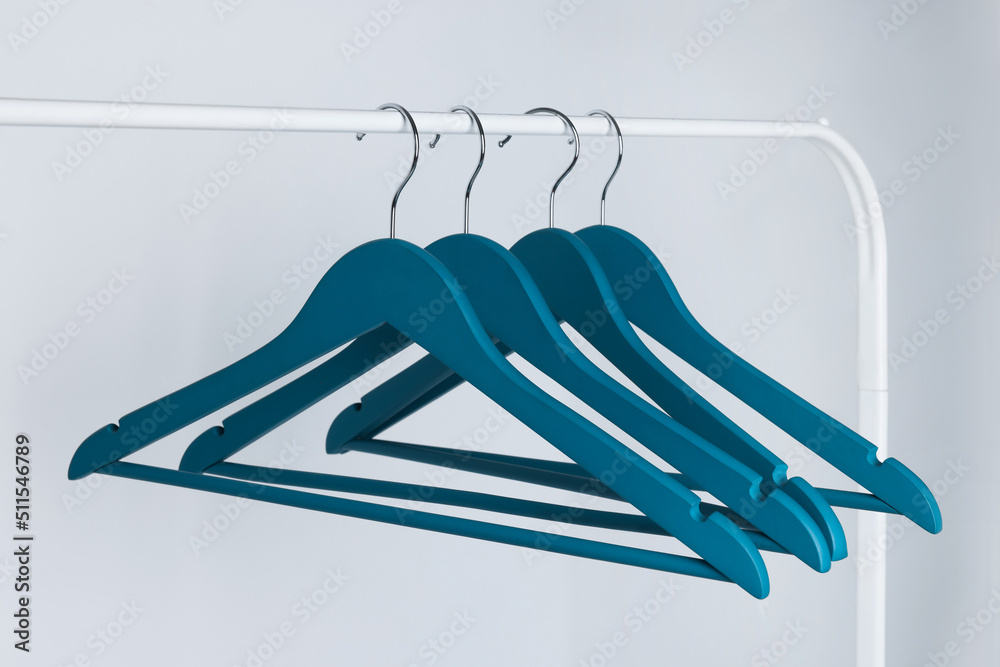 Blue clothes hangers on metal rack against light background Stock Photo