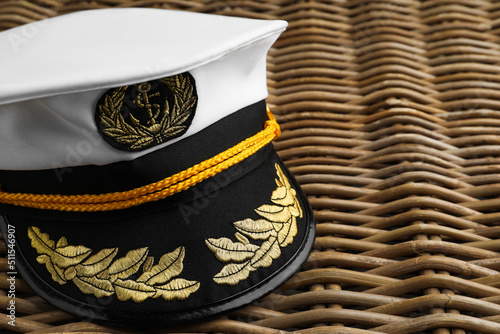 Peaked cap with accessories on wicker surface, closeup. Space for text